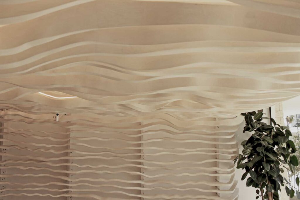 Vista de detalle de ondulaciones doble curvatura en madera de fresno, diseñadas mediante algoritmos de optimización y fabricadas digitalmente.